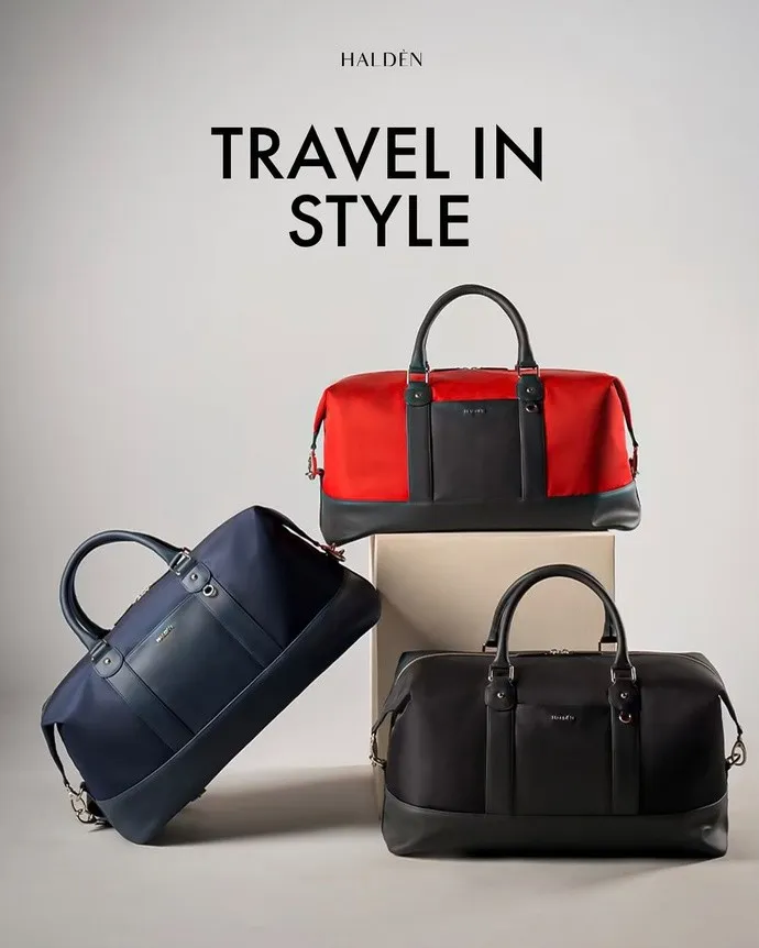 Three Halden travel bags in red, navy and black stacked on plinths