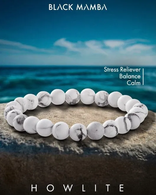 Black Mamba white howlite bead bracelet on sand with the sea behind